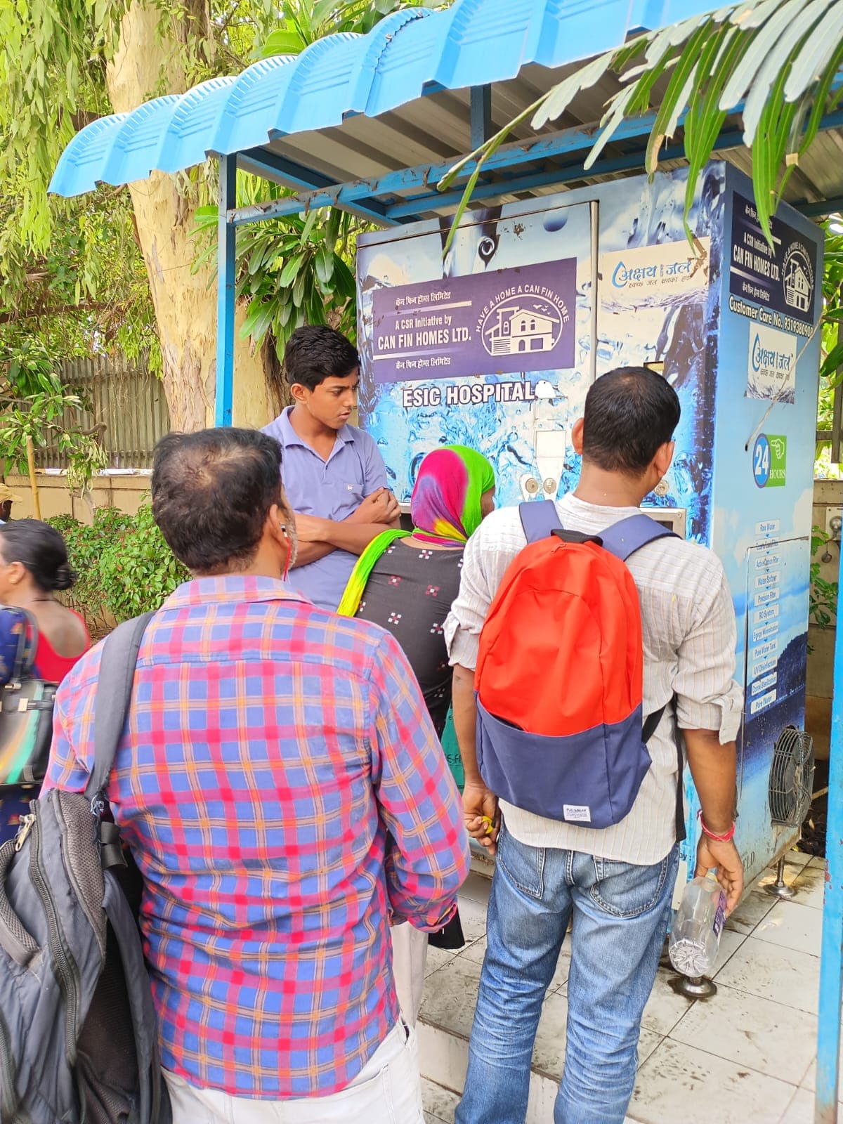 Maintenance engineers checking a kiosk's smart interface on a tablet at an urban transit hub at night