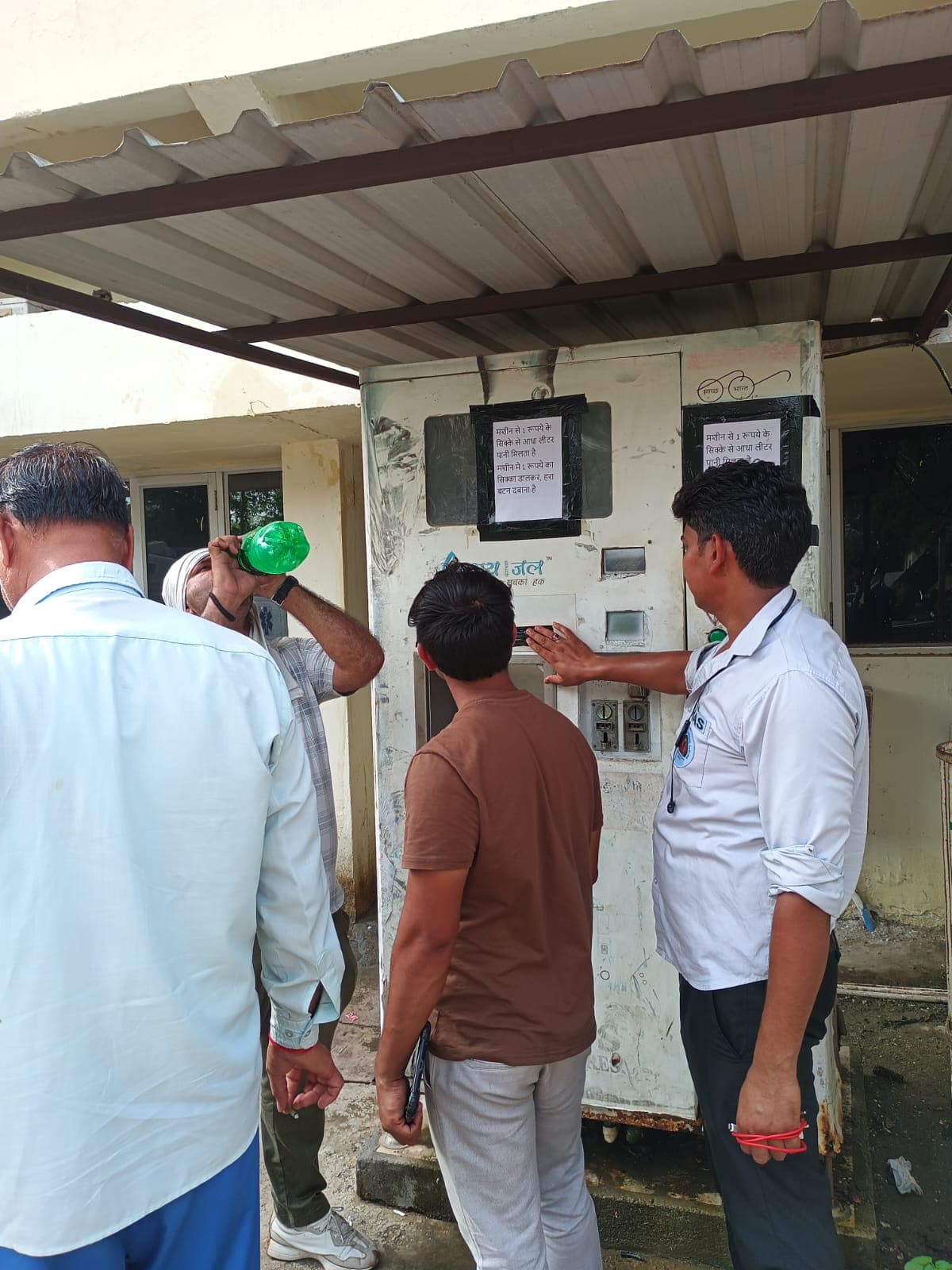 Maintenance engineers checking a kiosk's smart interface on a tablet at an urban transit hub at night