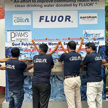 A custom-branded Swachh Jal Ghar kiosk at a hockey stadium surrounded by athletes and spectators